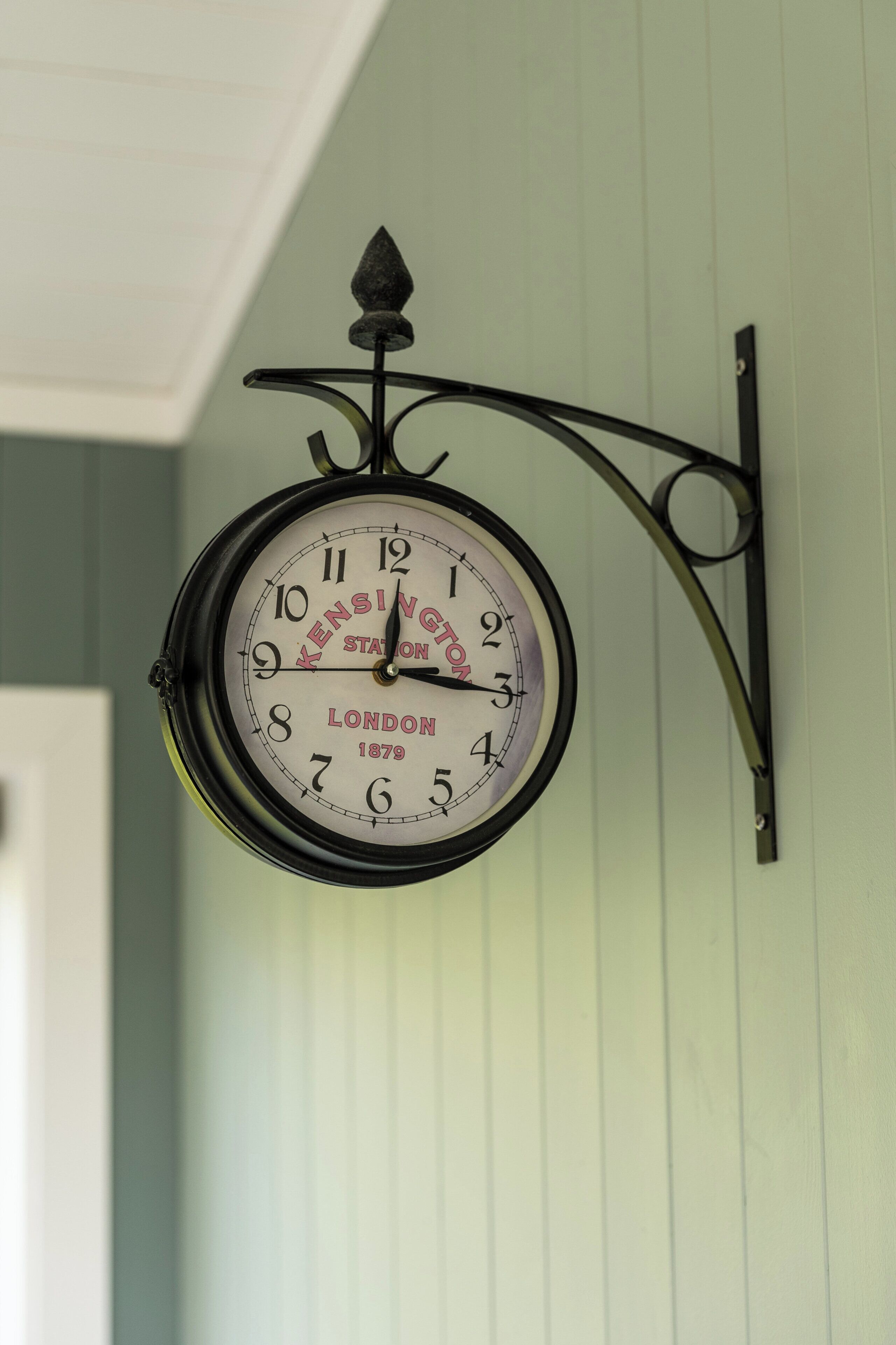 A wall-mounted clock with a classic design, featuring the brand name and location.
