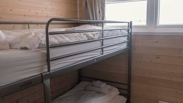 Een slaapkamer met een stapelbed, houten wanden, een raam en een plafondlamp.