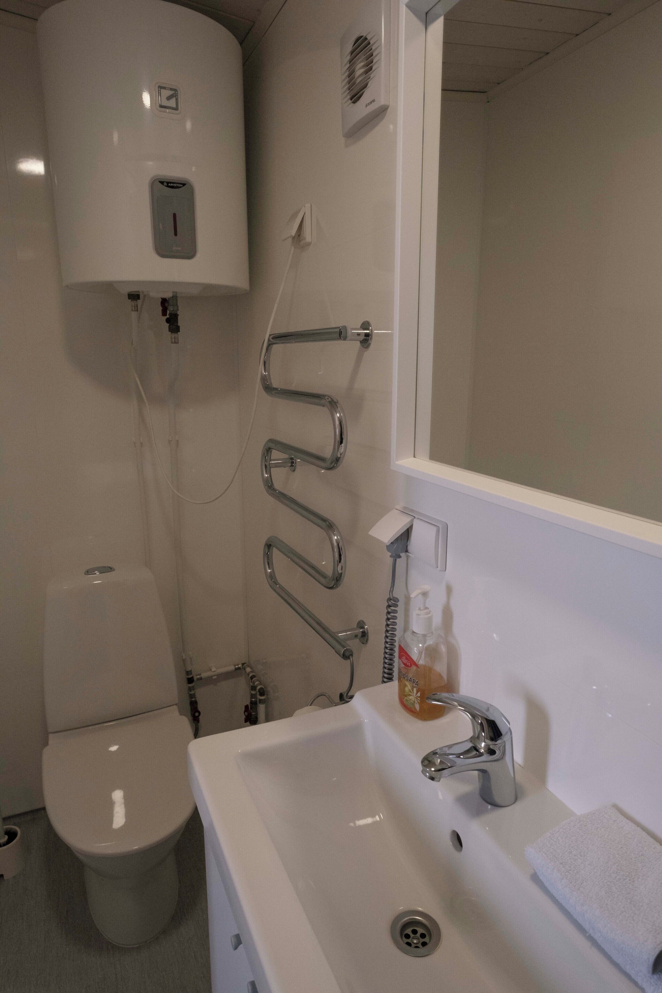Une salle de bain équipée de toilettes, d’un lavabo avec un miroir et d’une douche avec un sèche-mains.