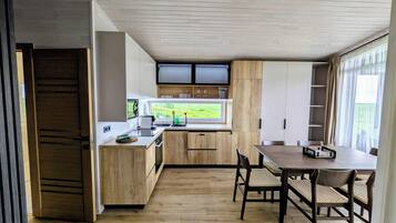 Una cocina moderna con armarios de madera, un comedor con mesa y sillas, y vistas a zonas verdes.