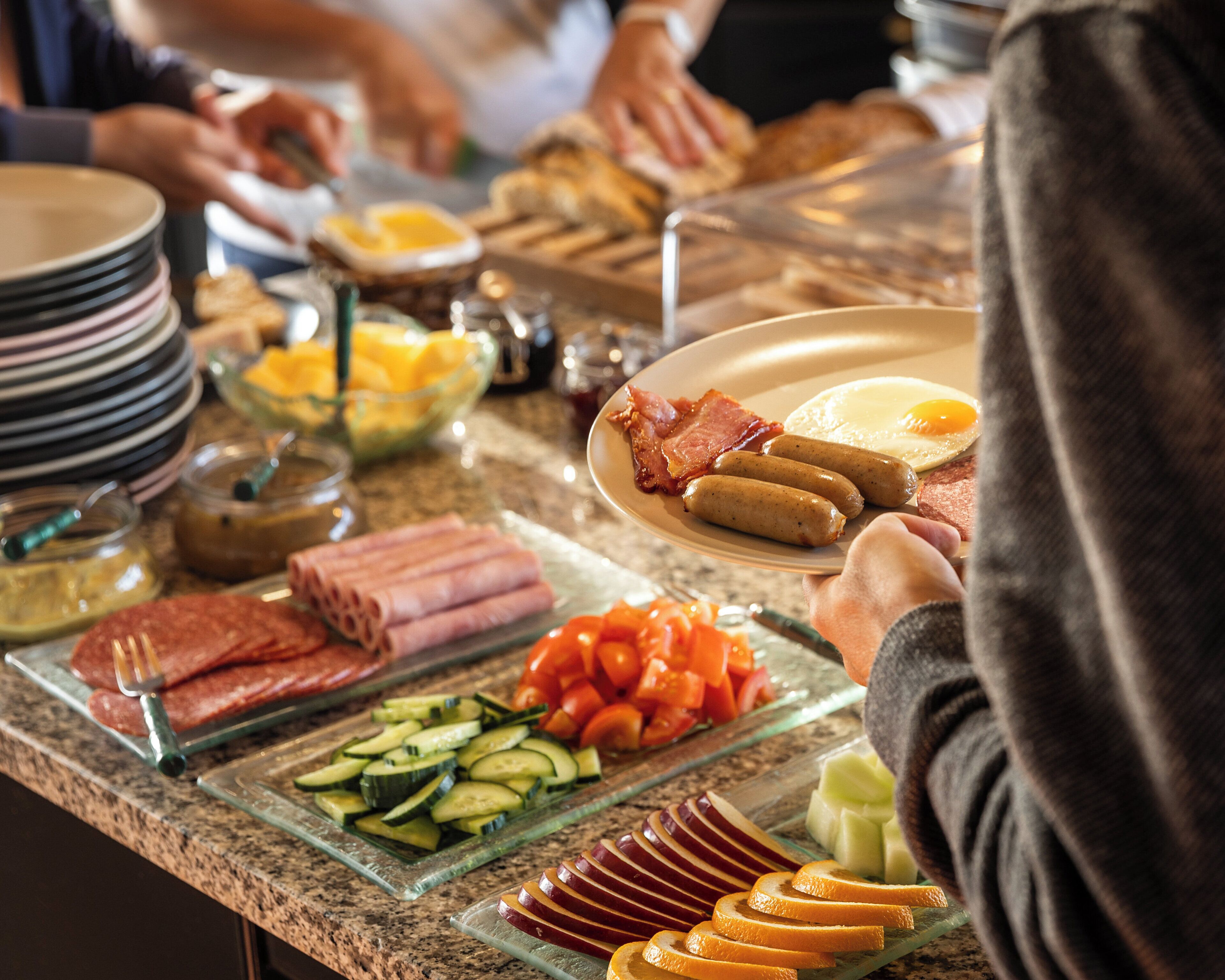 A buffet with various food items including meats, vegetables, and fruits.