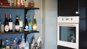Una cocina con estantes llenos de botellas de licor, una cava de vinos y un horno empotrado.