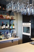 Una cocina con estantes llenos de botellas de licor, una cava de vinos y un horno empotrado.