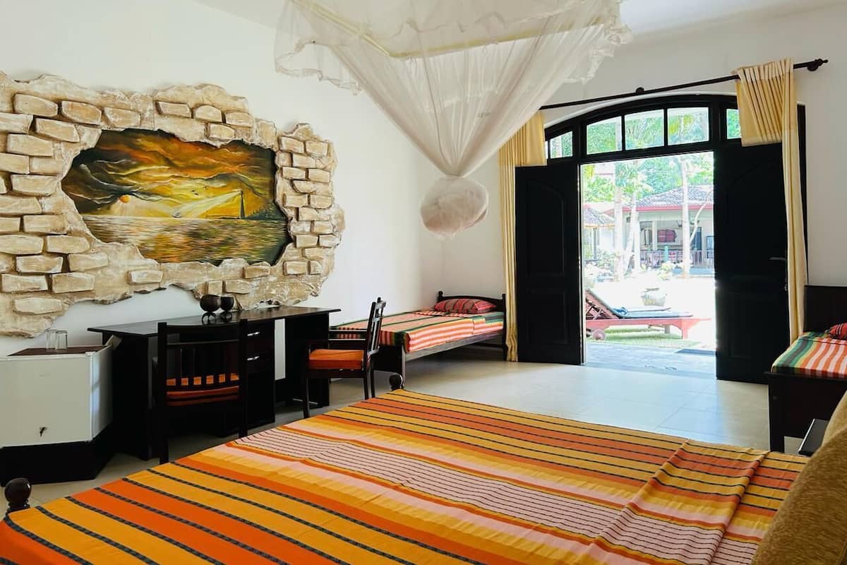 Un dormitorio con cama, escritorio, silla, ventana y vistas al exterior.
