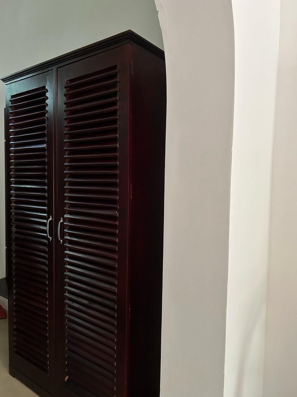 A dark wooden wardrobe with horizontal slats and a handle.