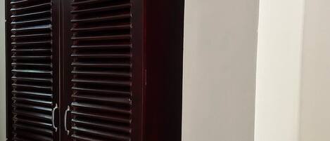 A dark wooden wardrobe with horizontal slats and a handle.