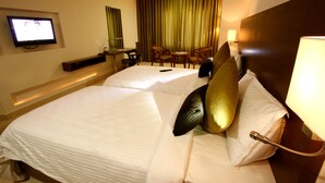 A hotel room with two beds, a television, a desk, and a chair. - Grand Continent Secunderabad A Sarovar Portico Affiliate Hotel (Hyderabad)