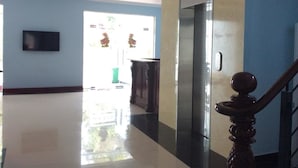 A modern lobby with a polished floor, a wall-mounted television, and a staircase with a wooden handrail. - Huy Hoang Hotel (Phu Quoc)