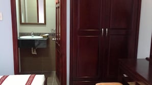 A bathroom with a sink, mirror, and wooden wardrobe. - Huy Hoang Hotel (Phu Quoc)