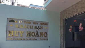 A building entrance with a sign in Vietnamese, a blue wall, and a glass door with cartoon characters. - Huy Hoang Hotel (Phu Quoc)