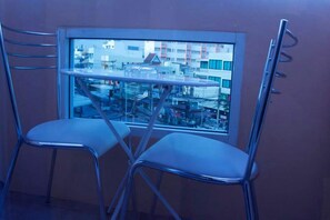 A room with two metal chairs and a small table in front of a window overlooking a cityscape. - 999 Triple Nine Boutique Hotel (Hua Hin)