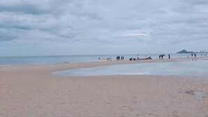 A beach with a wide sandy shore, calm water, and a distant mountain. - 999 Triple Nine Boutique Hotel (Hua Hin)