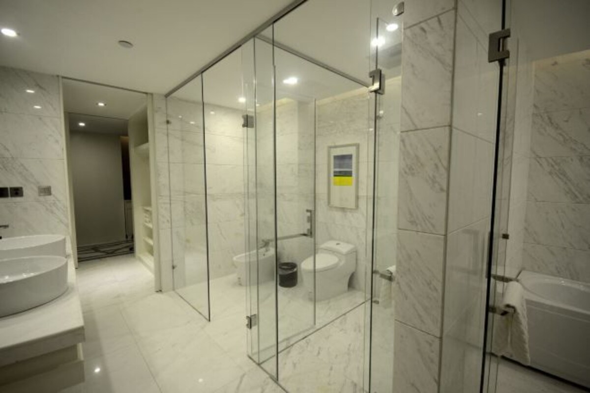 A modern bathroom with a glass-enclosed shower, a marble sink, and a toilet.
