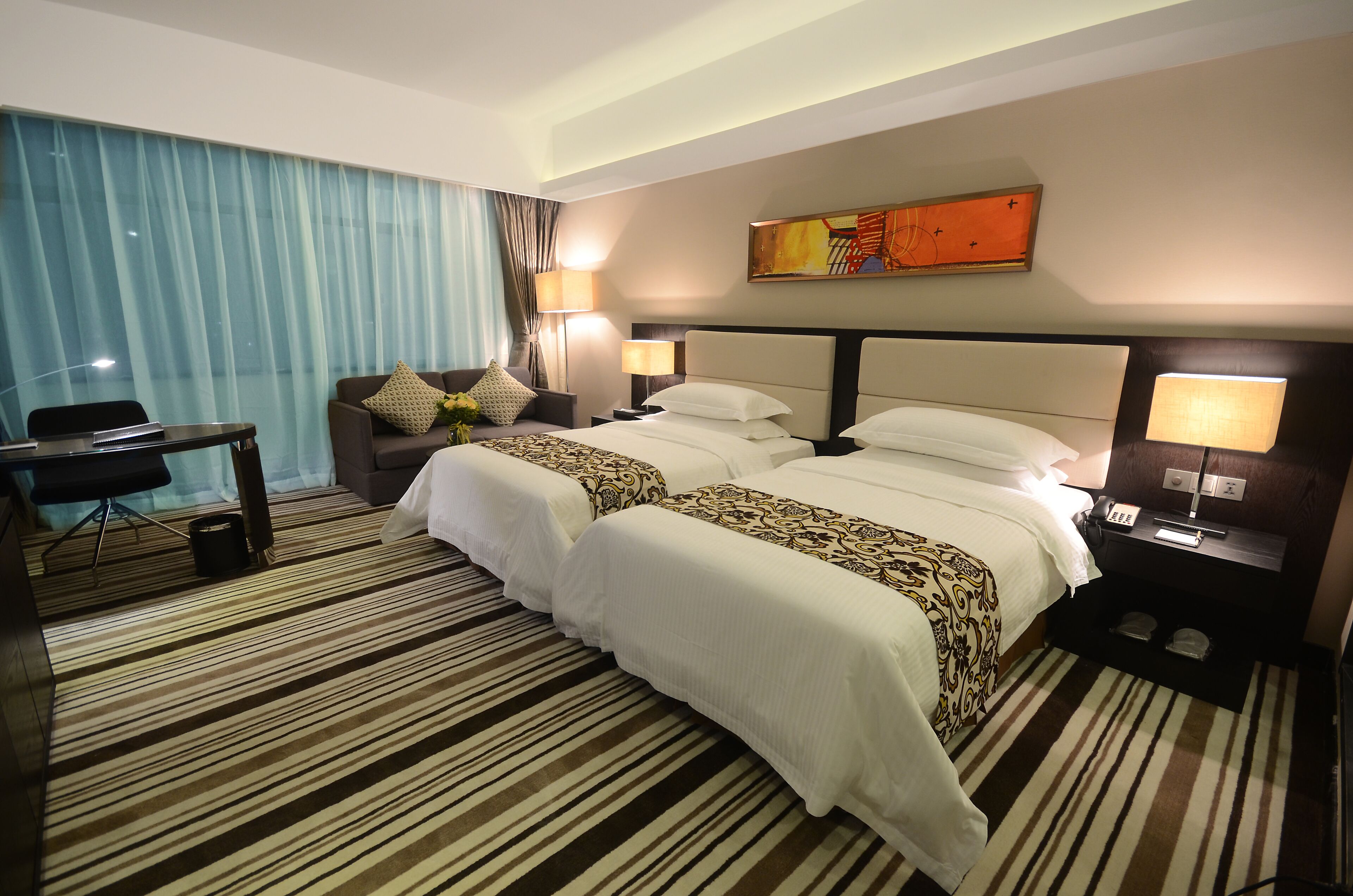 A hotel room with two beds, a desk, and a chair.
