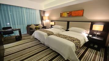 Habitación de hotel con dos camas, un escritorio y una silla.