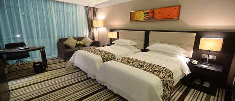 A hotel room with two beds, a desk, and a chair.