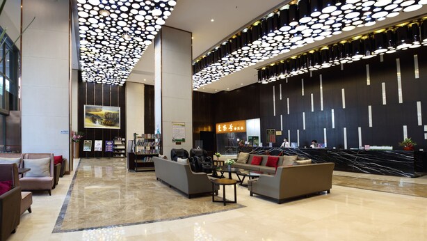 Um lobby moderno com balcão de recepção, área de estar e uma parede grande com linhas verticais.