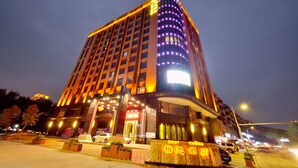 Een modern hotel met een gebogen gevel, verlichte signage en een opvallende ingang.