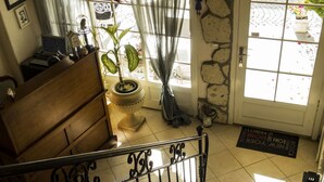 Una escalera con barandilla de metal, un banco de madera, una planta en maceta y una puerta con felpudo.