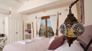 Un dormitorio con cama, lámpara colgante, armario y ventana con cortinas.