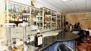 A bar area with shelves of liquor bottles, a bar counter, and several stools. - Paradise Hotel (Lomé)