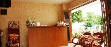A reception area with a wooden desk, a clock, and a television on the wall.