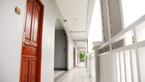 A corridor with wooden doors, white walls, and a tiled floor.