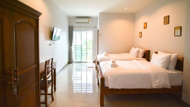 A hotel room with two beds, a TV, an air conditioning unit, and a view of the outdoors.