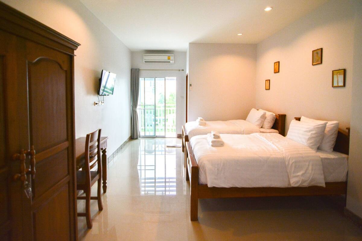 Quarto de hotel com duas camas, televisão, ar condicionado e vista para o exterior.