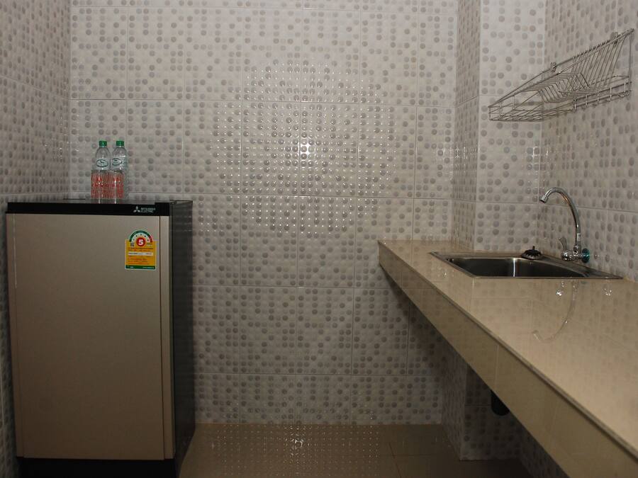 A small kitchenette with a refrigerator, a sink, and a tiled backsplash.