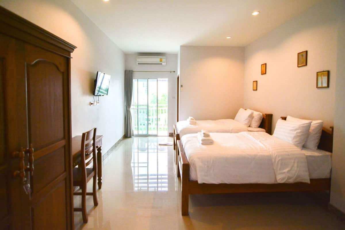 Quarto de hotel com duas camas, televisão, ar condicionado e vista pela janela.