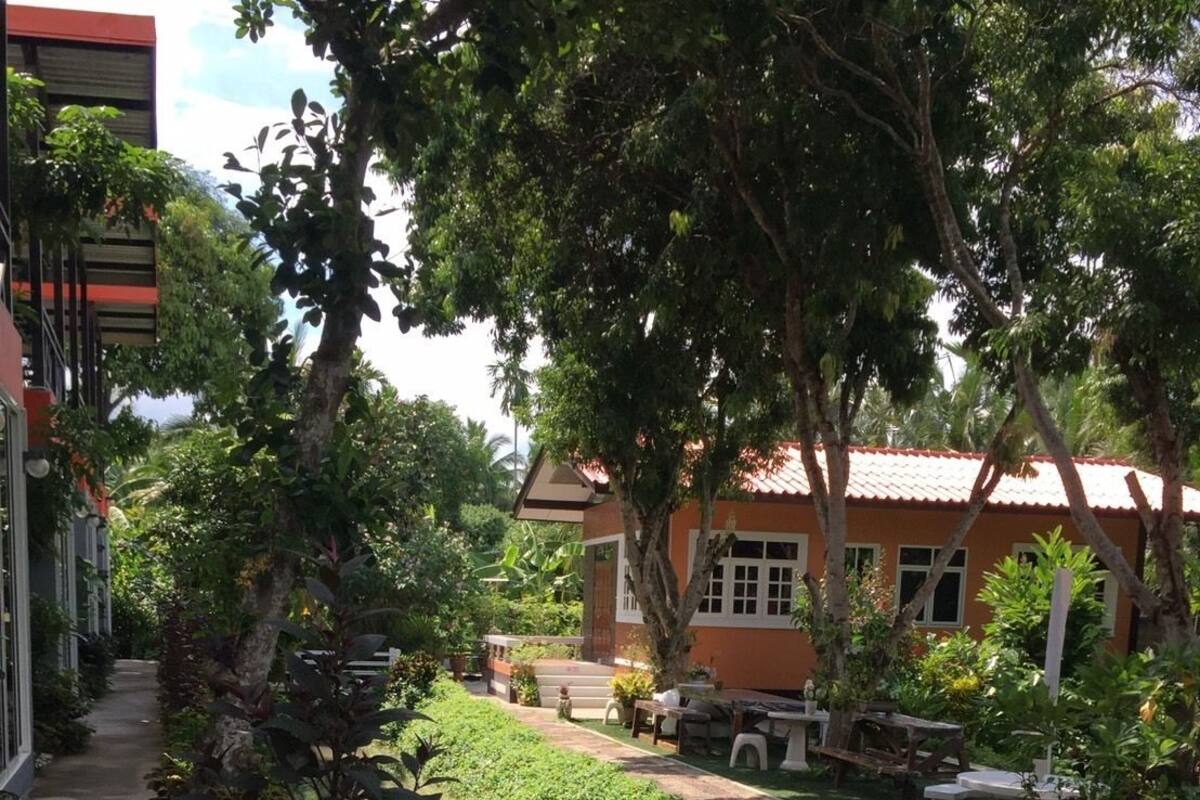 A serene garden with a water feature, lush greenery, and a building with a red roof.