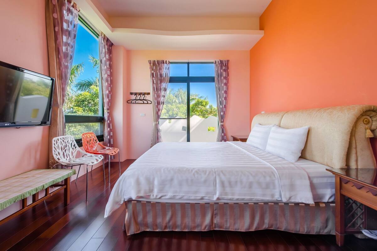 A bedroom with a bed, a TV, a desk, and a chair.