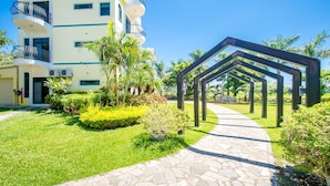 A multi-story building with balconies, a paved pathway, and surrounding greenery.