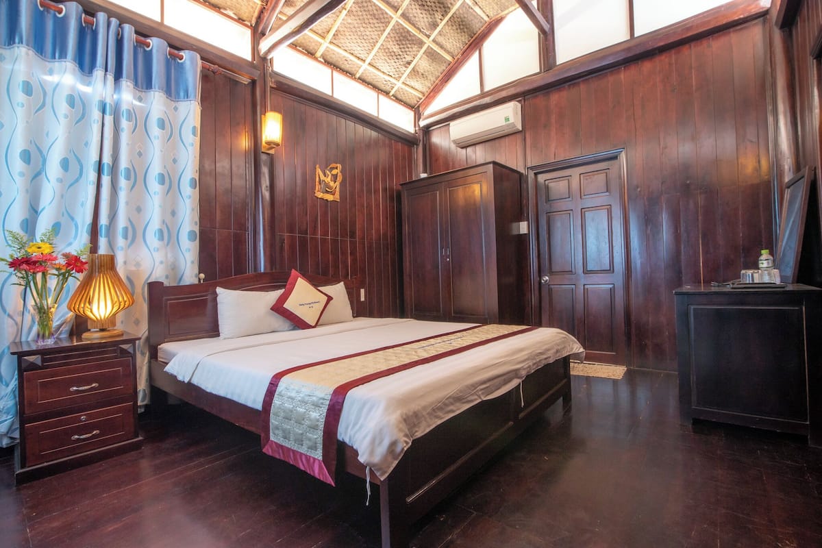 A wooden-paneled bedroom with a bed, nightstands, and a wardrobe.