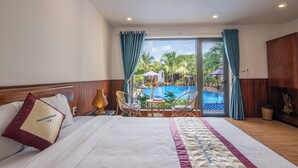 Une chambre d’hôtel avec un lit, une vue sur une piscine et une table avec des chaises.