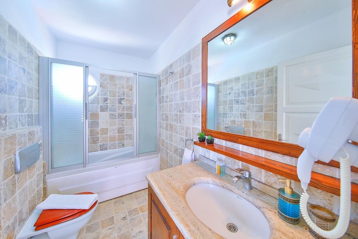 A bathroom with a glass shower enclosure, a white sink, and a large mirror.