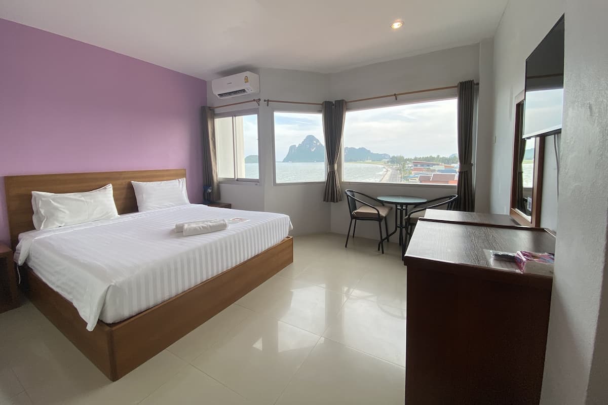 Quarto de hotel com cama, escrivaninha e vista para o mar.