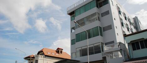 Een hotel met meerdere verdiepingen, een plat dak, grote ramen en een bord waarop staat Isuzu Hotel.