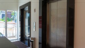 En moderne elevator med glasdør, skraldespand og brandalarm.