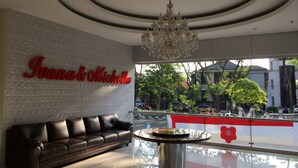 En moderne lobby med en lædersofa, en lysekrone og et skilt med teksten "Ivana & Michelle".