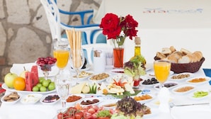 A table set with a variety of foods and drinks, including fruits, cheeses, bread, and a bottle of olive oil. - Alaroof Hotel  ( +15 ) (Cesme)