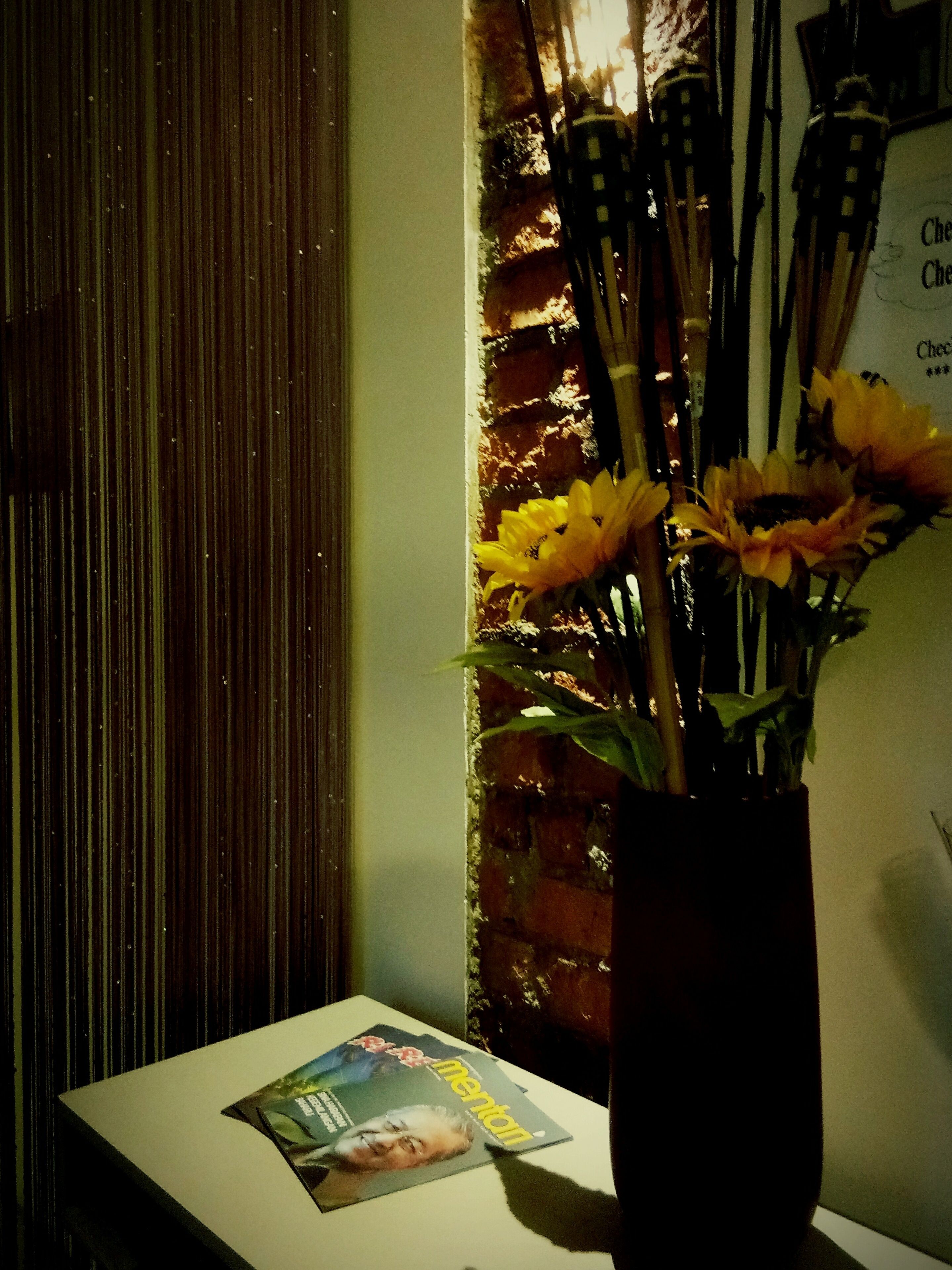 A table with a magazine and a vase of sunflowers.