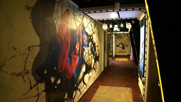 A corridor with a mural of Spider-Man, a wooden floor, and a wall with a crack. - Cinema Hotel UIBE (Beijing)