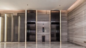A modern elevator area with three elevators, a control panel, and a marble floor. - JINGDUHUI Hotel (Dongguan)