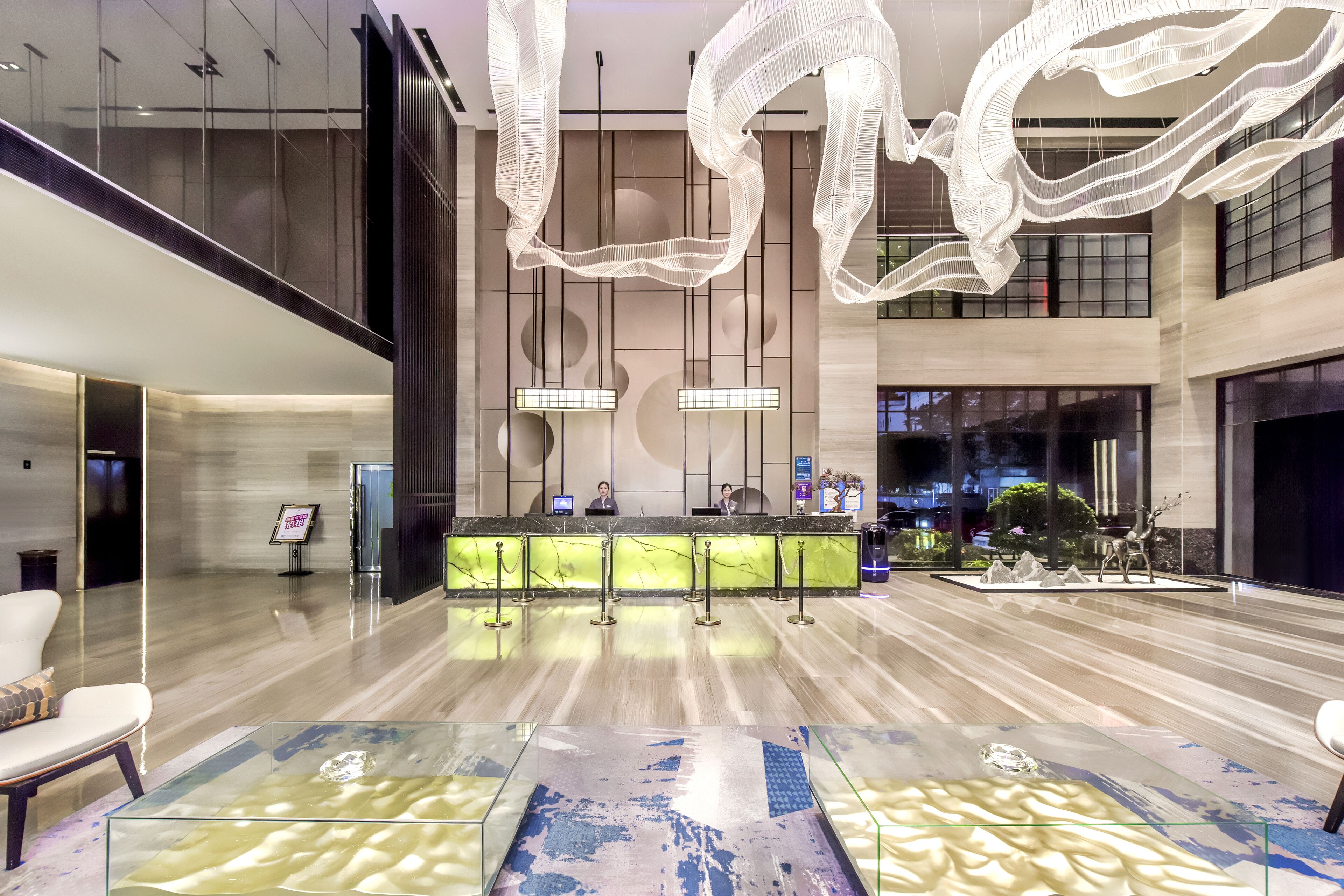 En moderne lobby med marmorgulv, en receptionsdisk og en stor lysekrone.