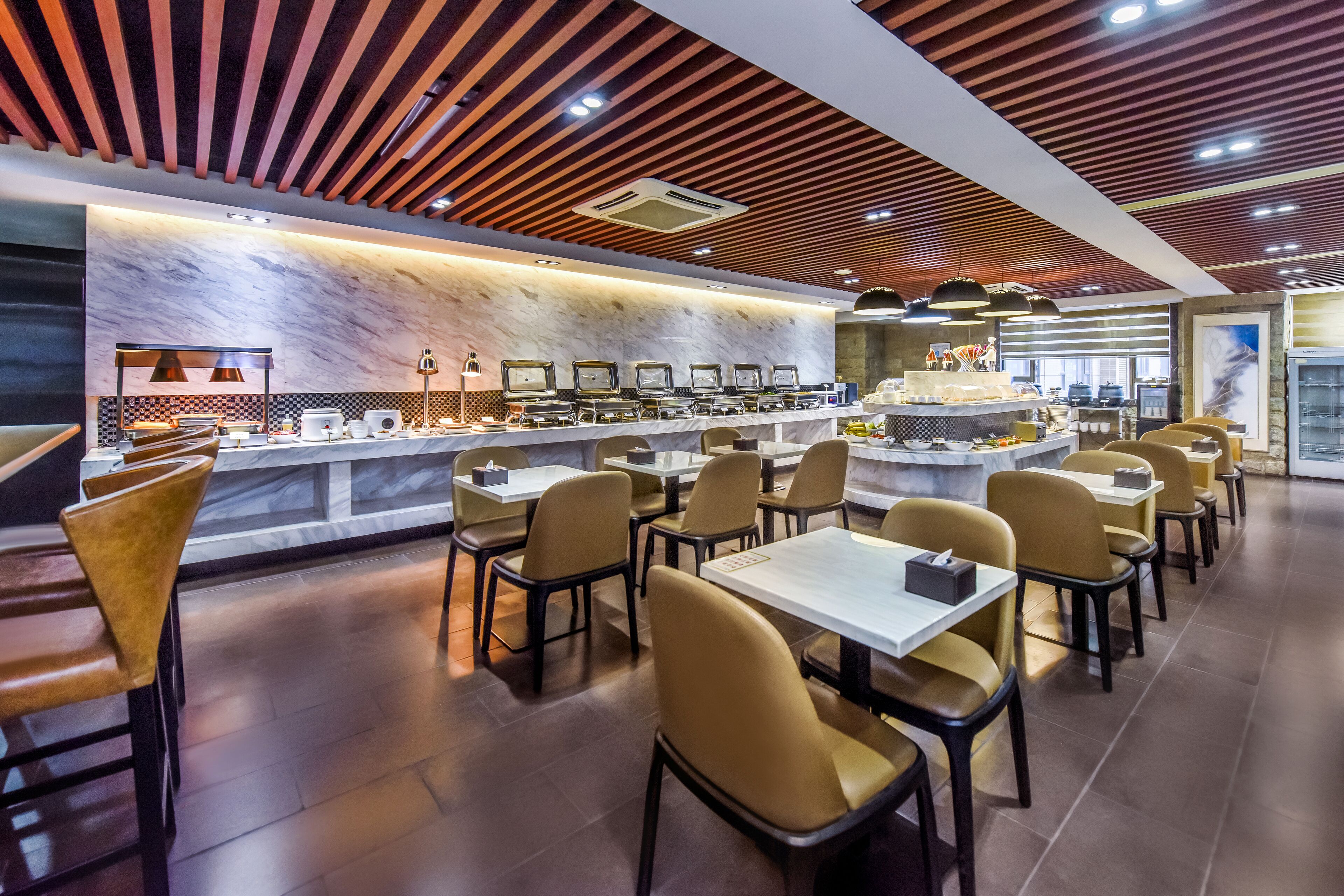 Um restaurante moderno com bancada de mármore, várias mesas e cadeiras.