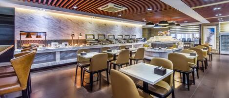 Um restaurante moderno com bancada de mármore, várias mesas e cadeiras.