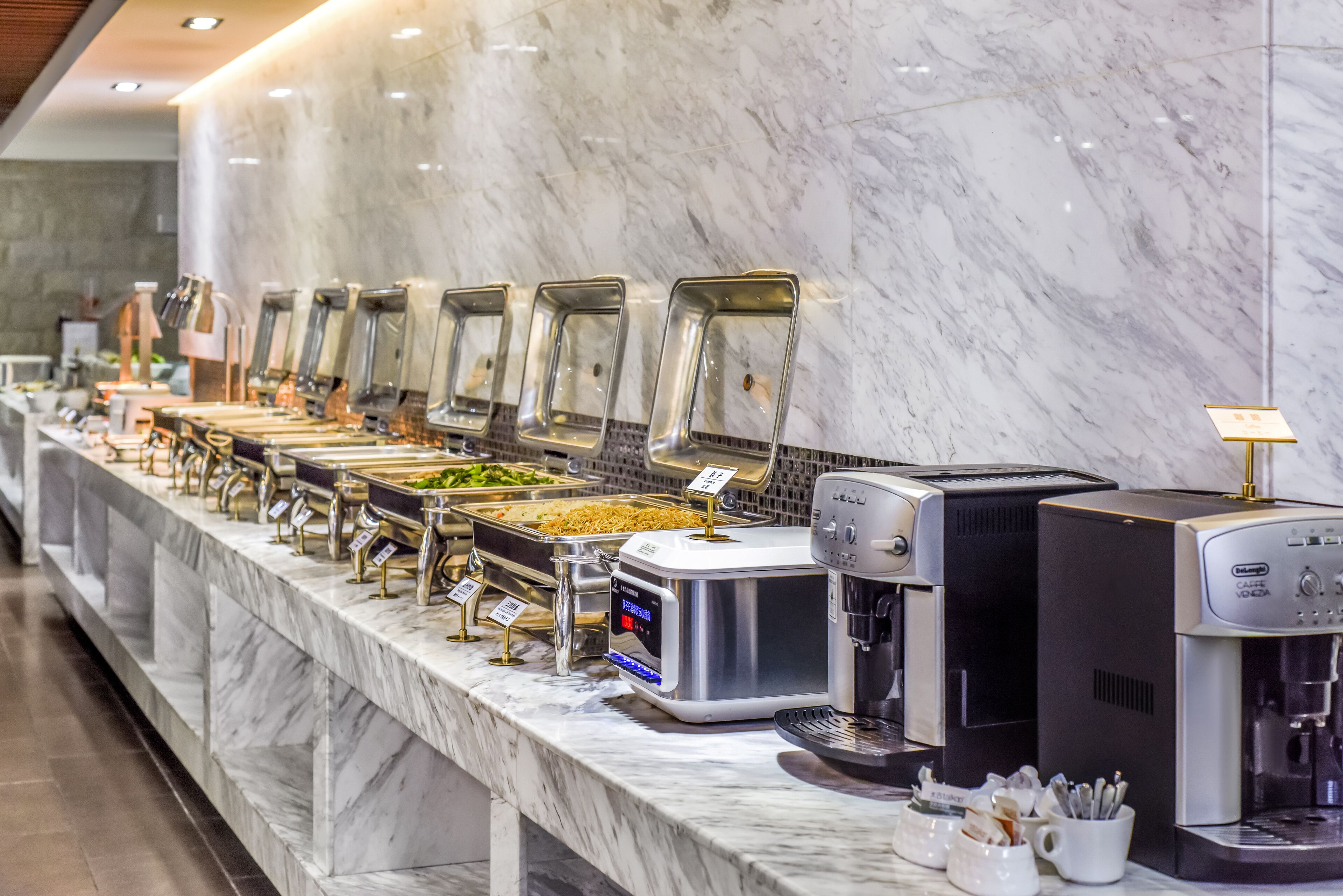 A buffet with various food stations and coffee machines.