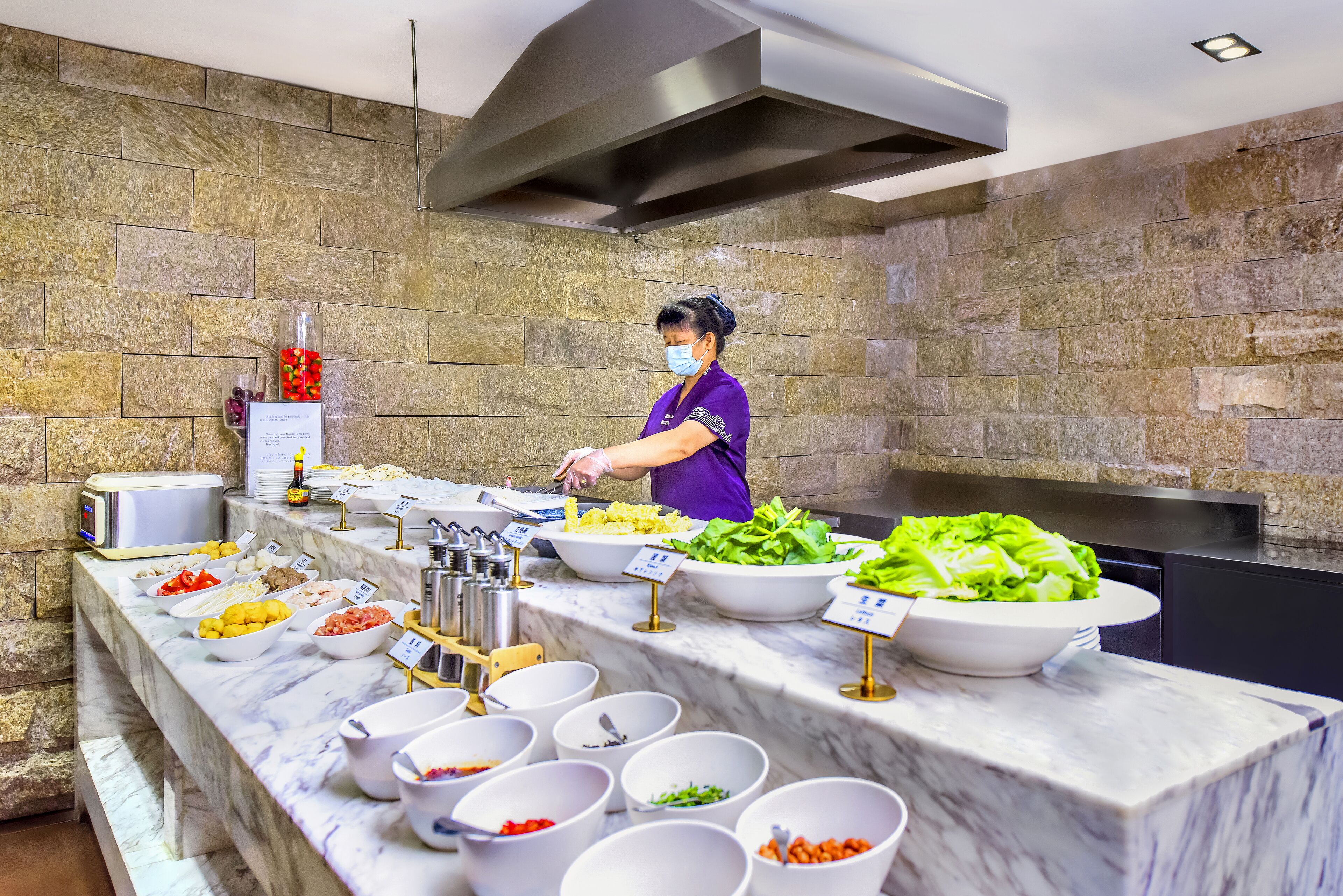 Montaje tipo buffet con diversos alimentos y un empleado sirviendo.